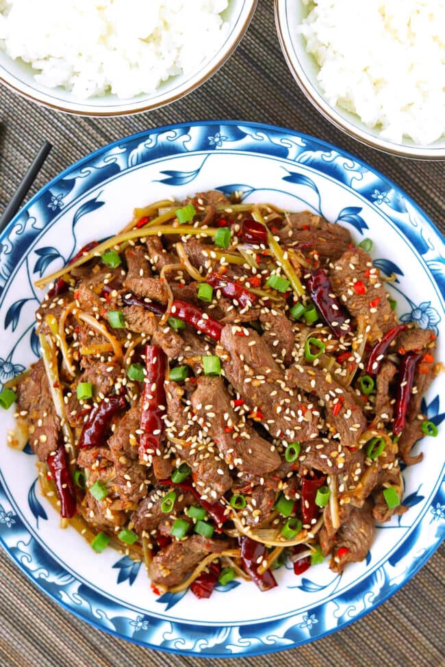 Mongolian lamb stir-fry on a plate and two rice bowls.