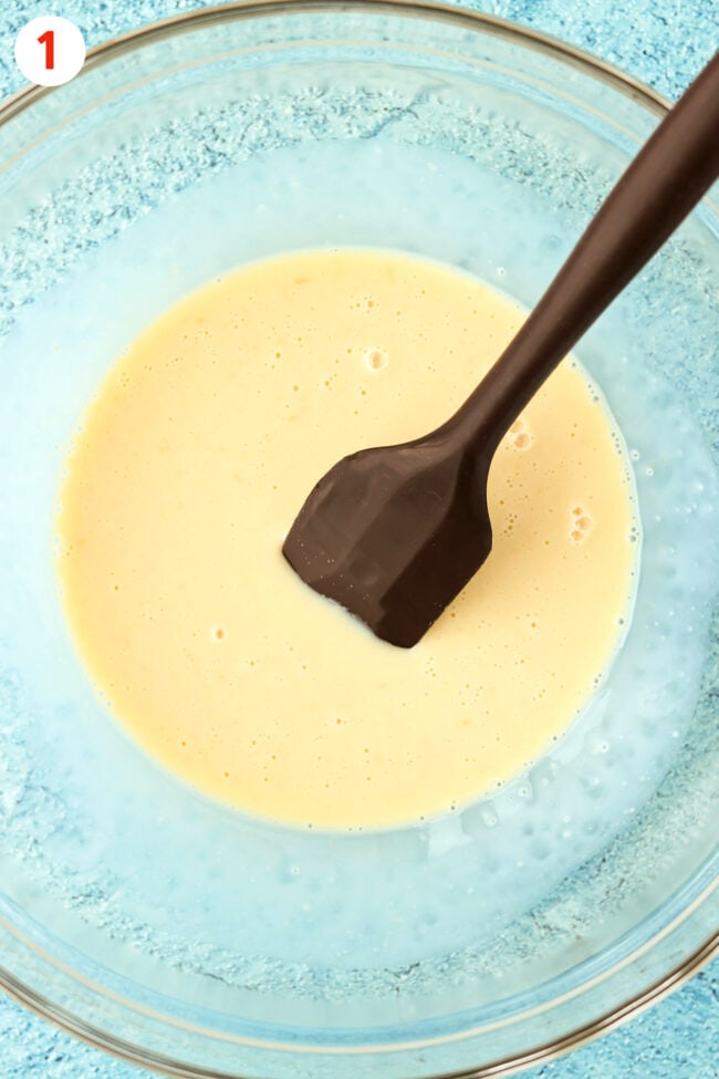 Sweetened condensed milk and flavorings mixture in a large mixing bowl with a spatula.