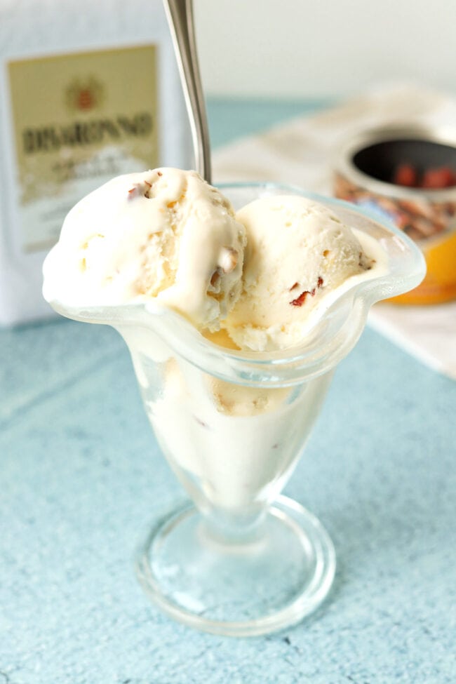 Ice cream scoops in a dessert glass with a spoon. Disaronno Velvet bottle behind.