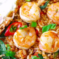 Closeup of shrimp fried rice on a plate. Text overlay "Thai Red Curry Fried Rice with Shrimp & Thai Style Fried Egg" and "thatspicychick.com".