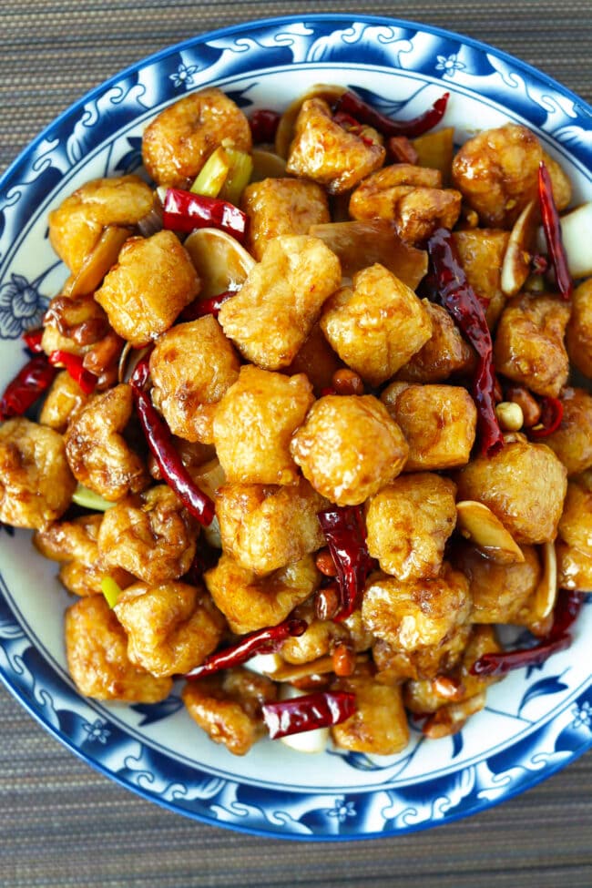 Closeup of kung pao tofu puffs on a blue rimmed plate.