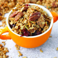 Granola in a bowl with handles. Text overlay "High Protein Granola", "Easy | Vegan | GF | DF", and "thatspicychick.com".