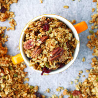 Granola in a bowl on a tray with granola. Text overlay "High Protein Granola", "Easy | Vegan | GF | DF", and "thatspicychick.com".