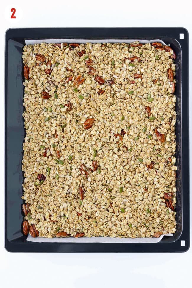Unbaked flattened granola mixture on a parchment paper lined baking tray.