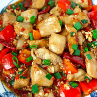 Closeup front view of plate with chicken stir-fry dish. Text overlay "Sichuan Garlic Chicken Stir-fry" and "thatspicychick.com".