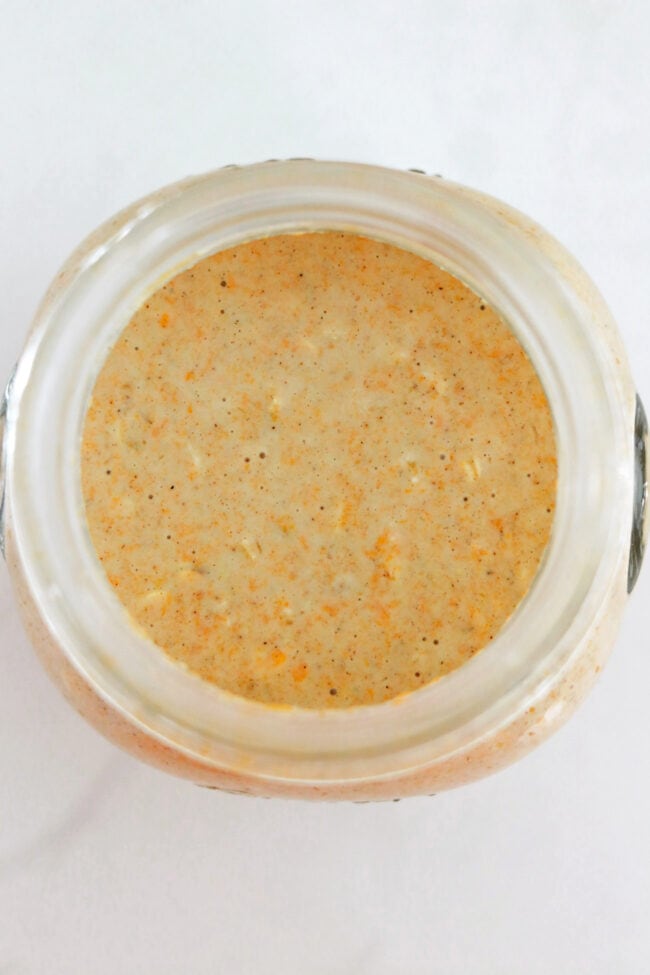Top view of mixed ingredients for pumpkin pie oats in a small jar.