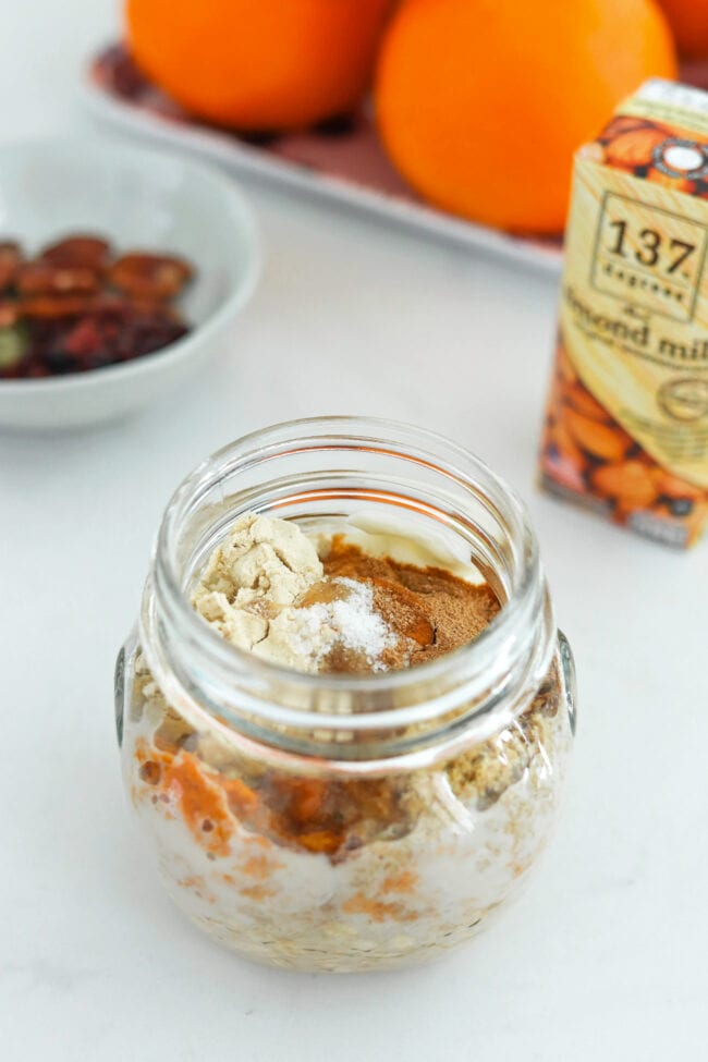 Unmixed ingredients for pumpkin pie oats in a small jar.