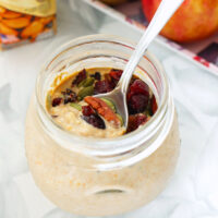Pumpkin overnight oats in a jar with a spoon and toppings. Text overlay "Pumpkin Spice Overnight Oats", "thatspicychick.com", and "High Protein, Easy | Healthy | Meal Prep".