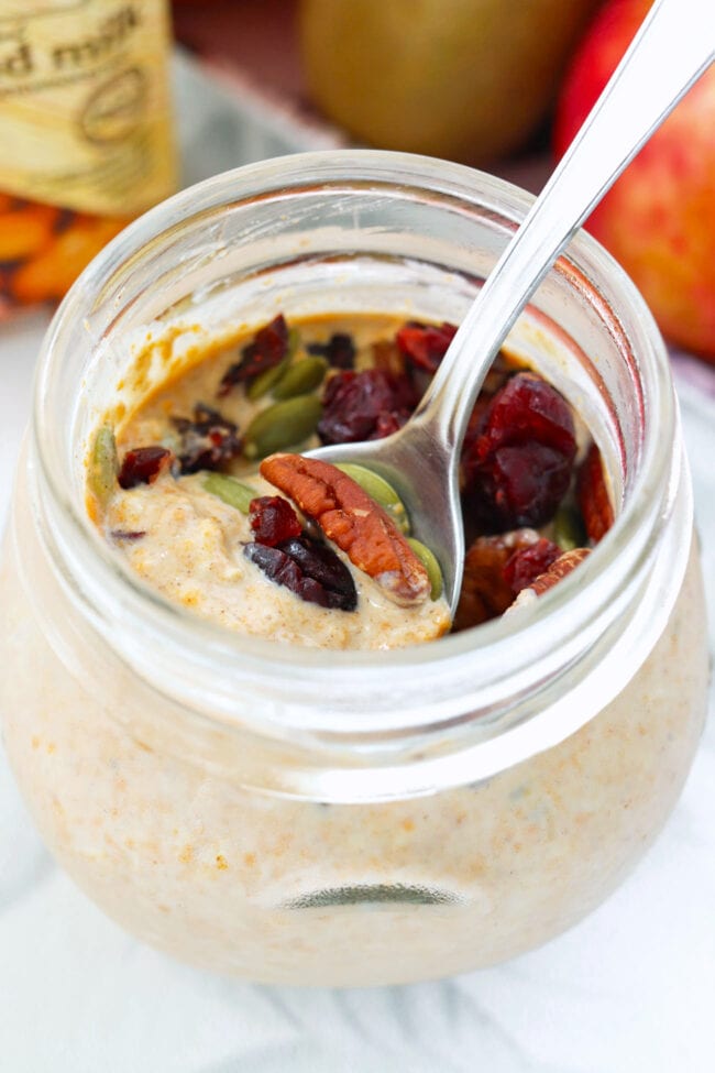 Closeup of jar with pumpkin overnight oats and a spoon inside.