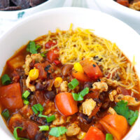Front view of bowls with chicken chili. Text overlay "Spicy Ground Chicken Chili" and "thatspicychick.com".