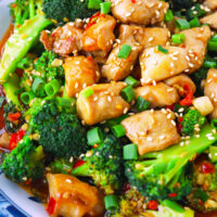 Closeup front view of plate with chicken and broccoli stir-fry dish. Text overlay "Chicken & Broccoli in Chili Garlic Sauce" and "thatspicychick.com".