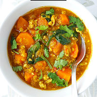 Two bowl with red lentil soup and spoons. Text overlay "Thai Red Curry Lentil Soup with Sweet Potatoes & Chicken" and "thatspicychick.com".