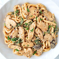 Plate with Creamy Mushroom Udon with Chicken topped with chopped parsley.