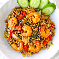 Plate with shrimp fried rice and cucumber slices. Text overlay "Spicy Thai Basil Shrimp Fried Rice" and "thatspicychick.com".