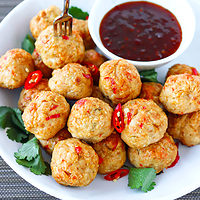 Plate with Thai chicken meatballs and bowl with sweet chili sauce. Text overlay "Baked Thai Chicken Meatballs" and "thatspicychick.com"