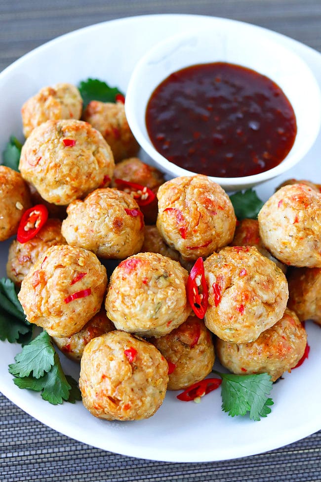 Closeup front view of plate with Thai chicken meatballs and bowl with Thai sweet chili sauce.