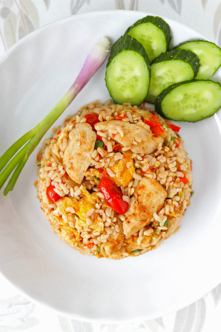 Closeup overhead shot of shirataki Thai fried rice on a plate with cucumber and spring onion.