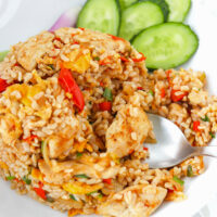 Spoon in a plate with fried rice and cucumber slices. Text overlay "Shirataki Thai Fried Rice" and "thatspicychick.com".