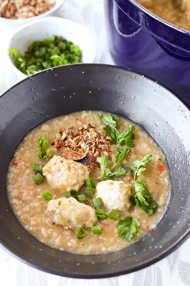 Front view of bowl and pot with Thai congee with chicken meatballs.