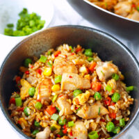 Front view of bowl and wok with fried rice. Text overlay "Spicy Chicken Fried Rice" and "thatspicychick.com".