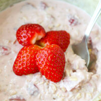 Closeup front view of bowl with spoon and strawberry protein overnight oats.