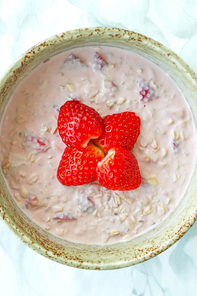 Bowl with strawberry protein overnight oats topped with fresh sliced strawberries.