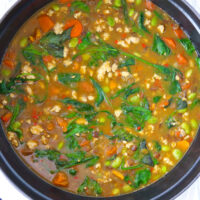 Top view of Dutch oven with green lentil soup. Text overlay "Thai Green Curry Lentil Soup" and "thatspicychick.com".