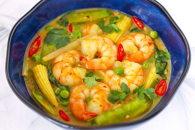 Front view of Thai green curry shrimp with vegetables in a blue bowl.