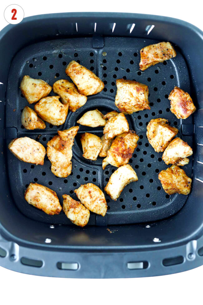 Cooked dices chicken in air fryer basket.