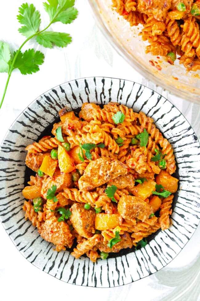 Plate and mixing bowl with creamy peri peri chicken pasta.