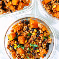 Ground chicken, sweet potato, black beans, corn garnished with coriander in meal prep containers.