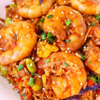 Closeup front view of fried rice with large shrimp on a plate. Text overlay "Korean Gochujang Fried Rice" and "thatspicychick.com".