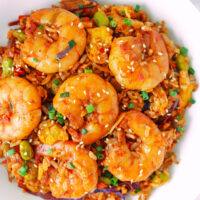 Closeup of fried rice with large shrimp on a plate. Text overlay "Gochujang Fried Rice with Jumbo Shrimp" and "thatspicychick.com".