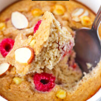 Spoon in ramekin to show texture of raspberry baked oatmeal. Text overlay "Raspberry White Chocolate Baked Oats" and "thatspicychick.com".