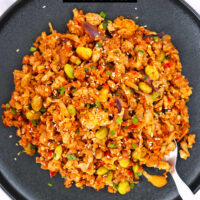 Gochujang cauliflower fried rice on a plate with a spoon. Text overlay "Korean Cauliflower Fried Rice" and "thatspicychick.com".