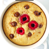 Chocolate chip baked oats with raspberries in a ramekin. Text overlay "Raspberry Chocolate Chip Baked Oats" and "thatspicychick.com".