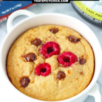 Baked oats with chocolate chip in a ramekin and protein powder tub behind. Text overlay "Raspberry Chocolate Chip Baked Oats" and "thatspicychick.com".