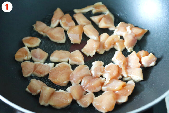 Marinated chicken pieced cooking in a wok.