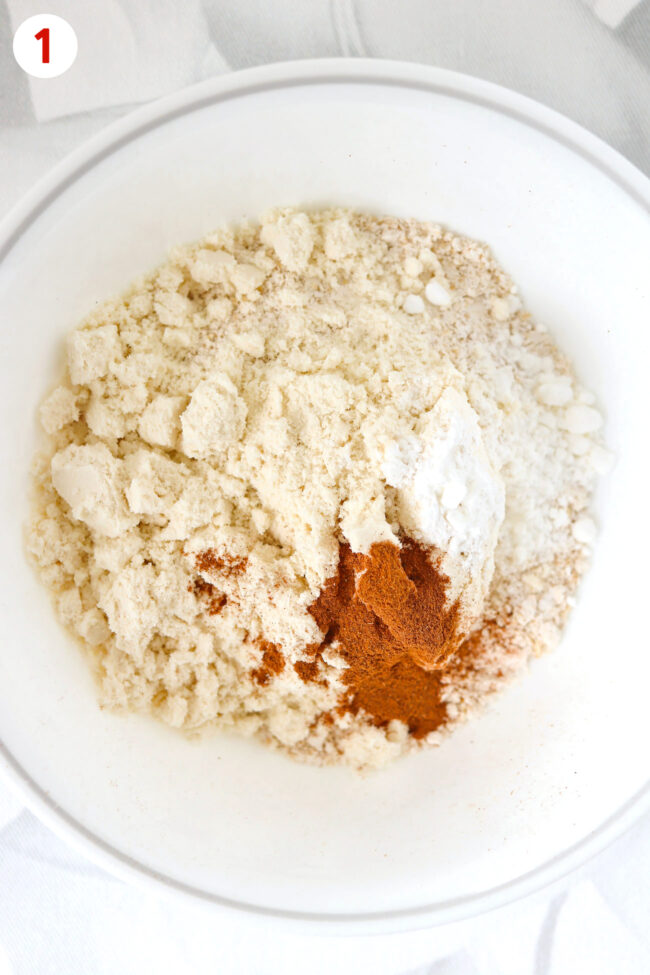 Blended oats, protein powder, ground cinnamon and baking powder in a bowl.