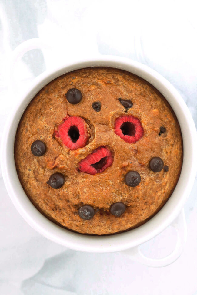 Top view of espresso chocolate chip baked oats with raspberries in a ramekin.
