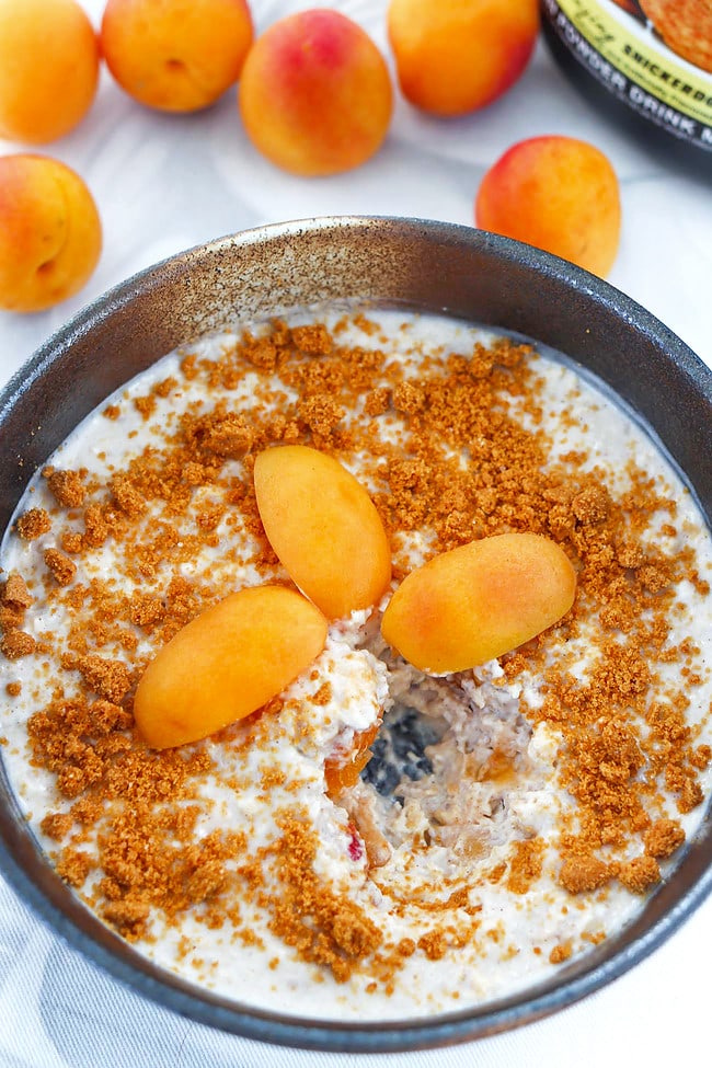 Bites eaten from bowl with Snickerdoodle Overnight Oats and apricots behind.