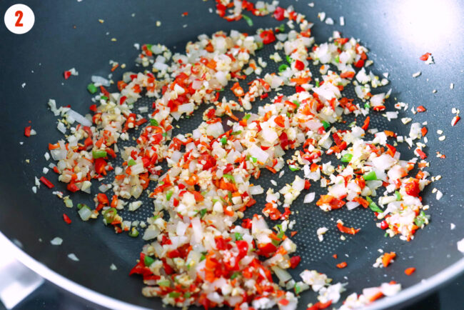 Stir-frying onion, garlic and chilies in a wok.