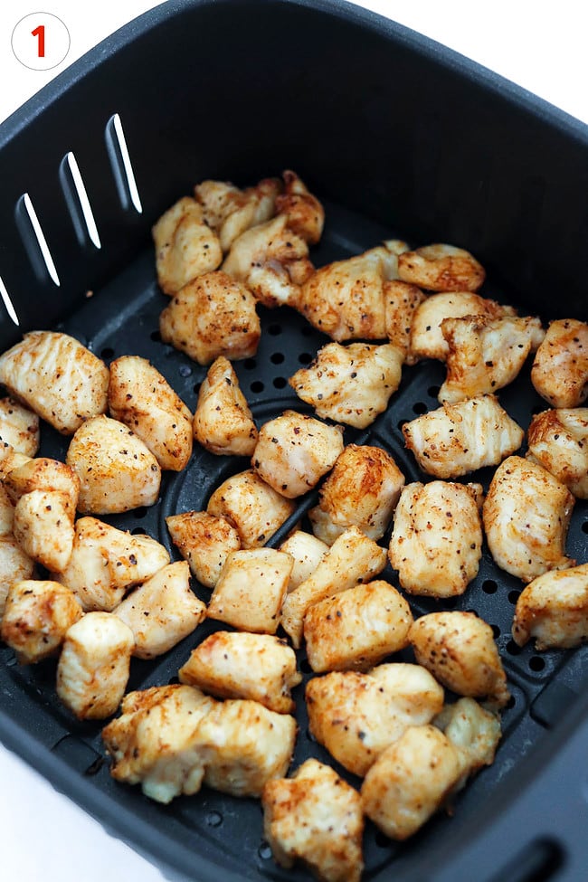 Cooked chicken pieces in air fryer basket.