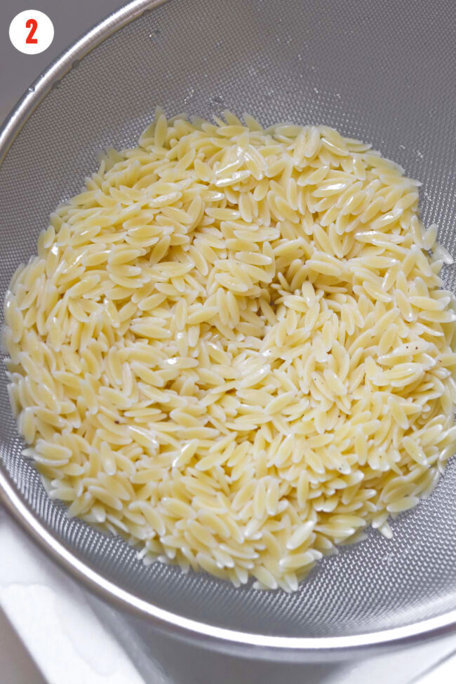 Cooked and drained orzo in a strainer.