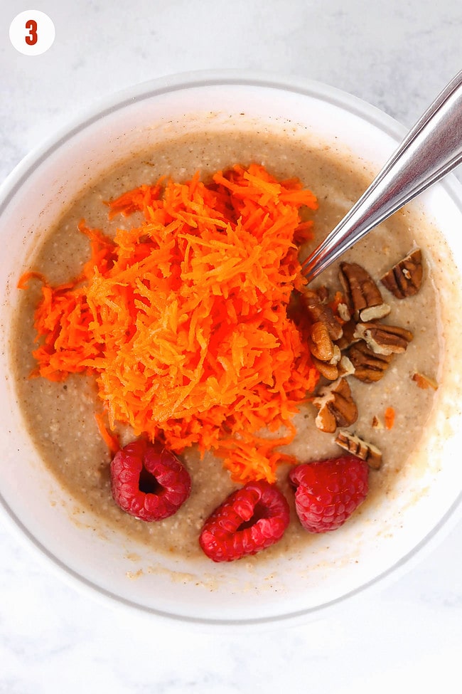Added raspberries, chopped pecans and grated carrots to batter in a bowl with spoon.