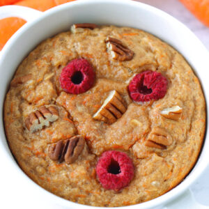 Closeup front view of carrot cake baked oats in a ramekin and carrots.