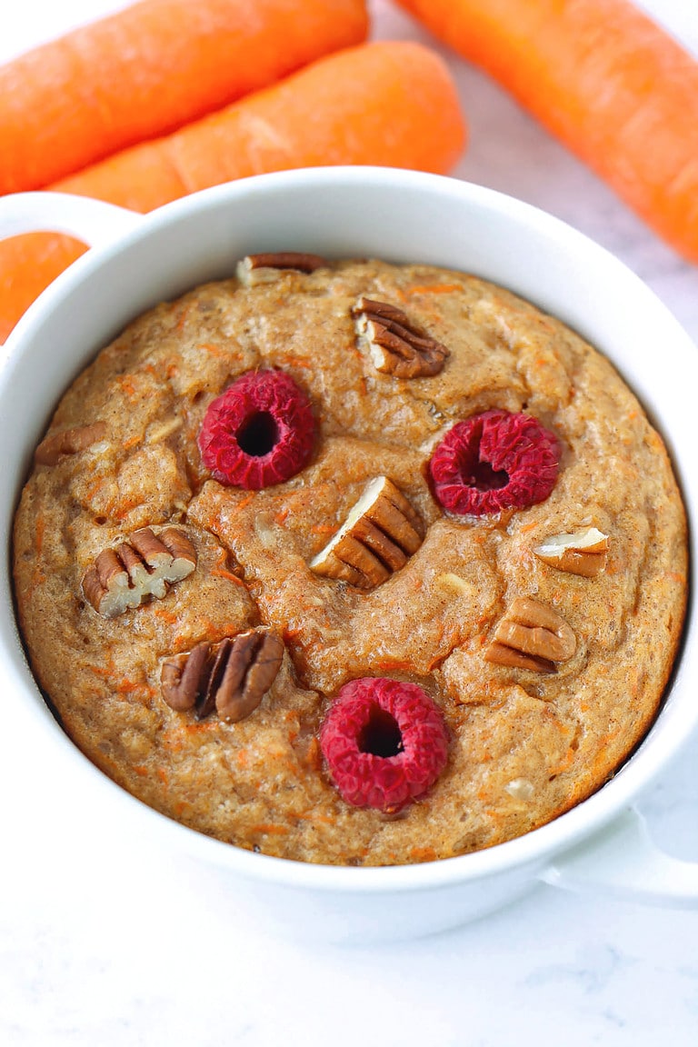 Closeup front view of carrot cake baked oats in a ramekin and carrots.
