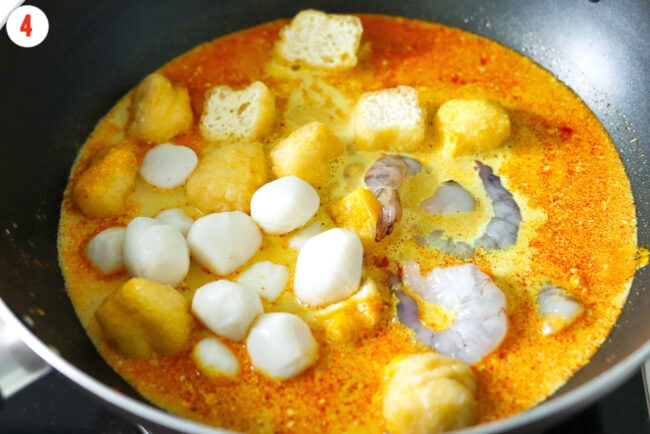 Added shrimp, fish balls and fried tofu puffs to wok with laksa broth.