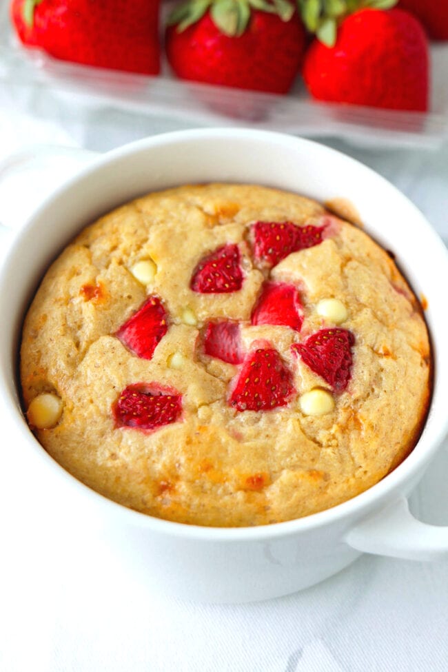 Closeup baked oats in ramekin front view with strawberries in box behind.