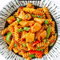 Closeup of plate with chicken pasta. Text overlay "One Pot Chicken Fajita Pasta" and "thatspicychick.com".